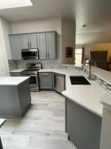 Modern kitchen remodel featuring gray cabinets, white quartz countertops, and a gray tile backsplash